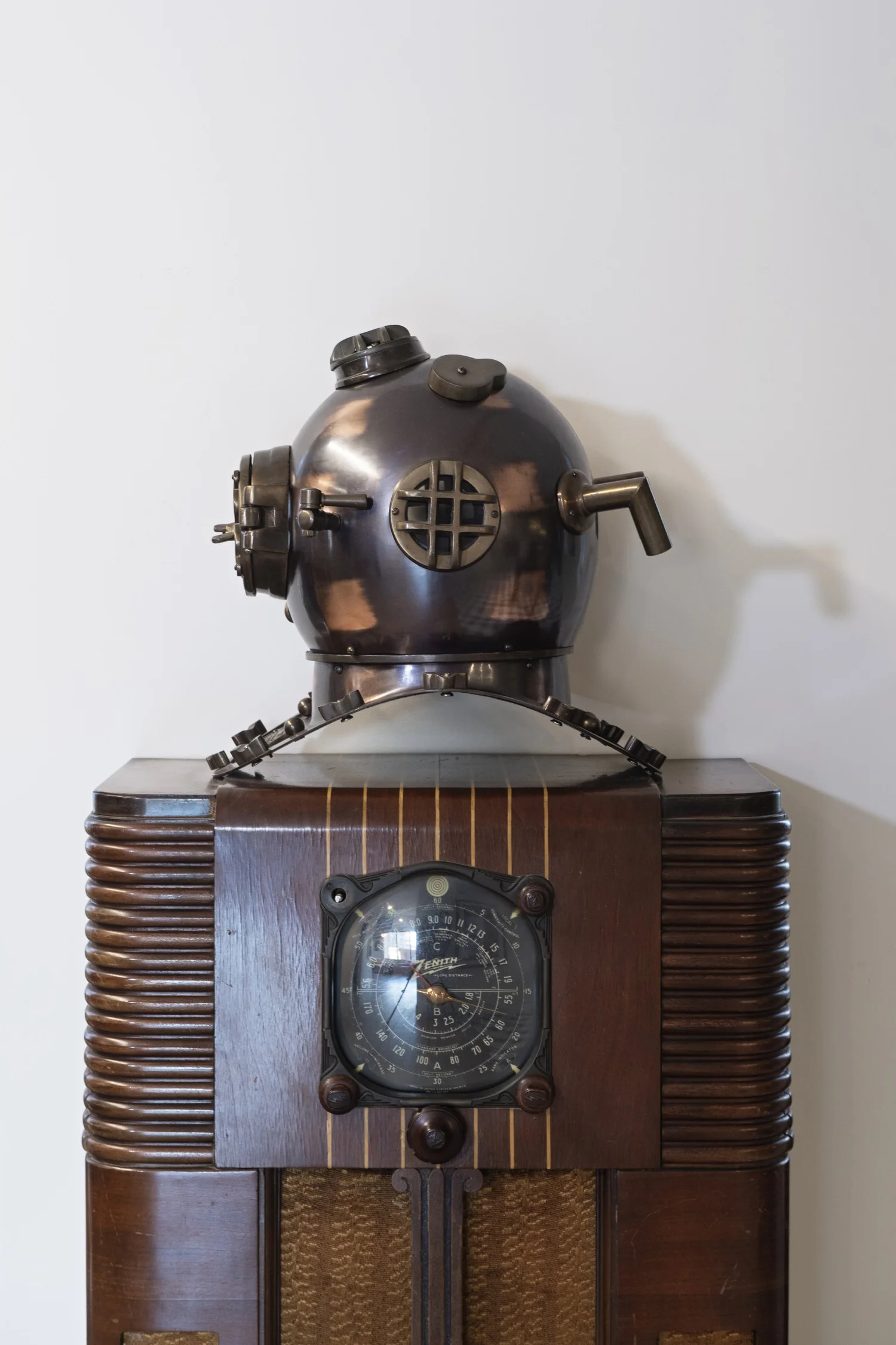 Antique brass diving helmet resting on a 1940s wooden Zenith radio